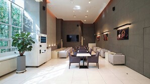 A modern hotel lobby with a seating area, a large TV screen, and artwork on the walls. - Uljiro Co-Op Residence (Seoul)