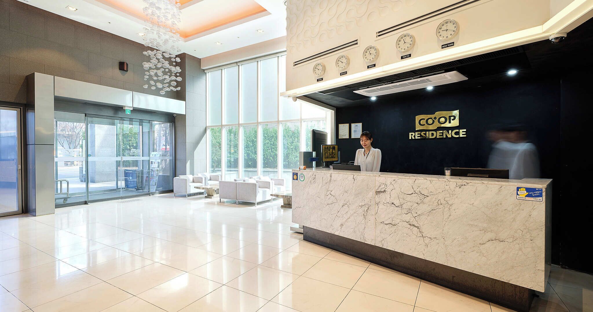 Un moderno vestíbulo de hotel con mostrador de recepción, zona de estar y grandes ventanales.