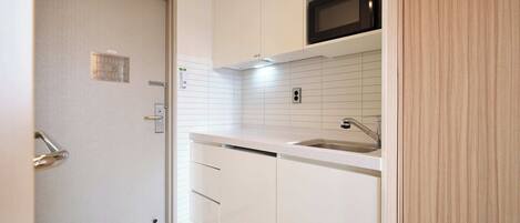 A kitchen with white cabinets, a stainless steel sink, and a microwave.