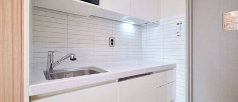 Una cocina moderna con un lavamanos de acero inoxidable, muebles de cocina blancos y un microondas sobre la encimera.
