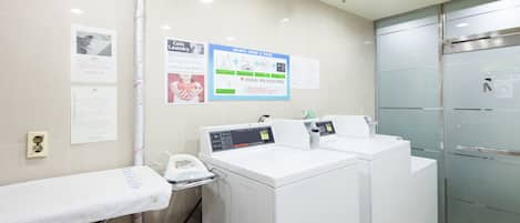 Une buanderie équipée de deux machines à laver, d’un sèche-linge et d’un téléphone fixé au mur.