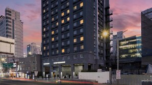 A multi-story hotel with a modern design, featuring a prominent entrance and a clear view of the surrounding urban environment. - Uljiro Co-Op Residence (Seoul)