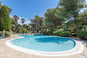 Una piscina al aire libre de temporada, sombrillas, tumbonas