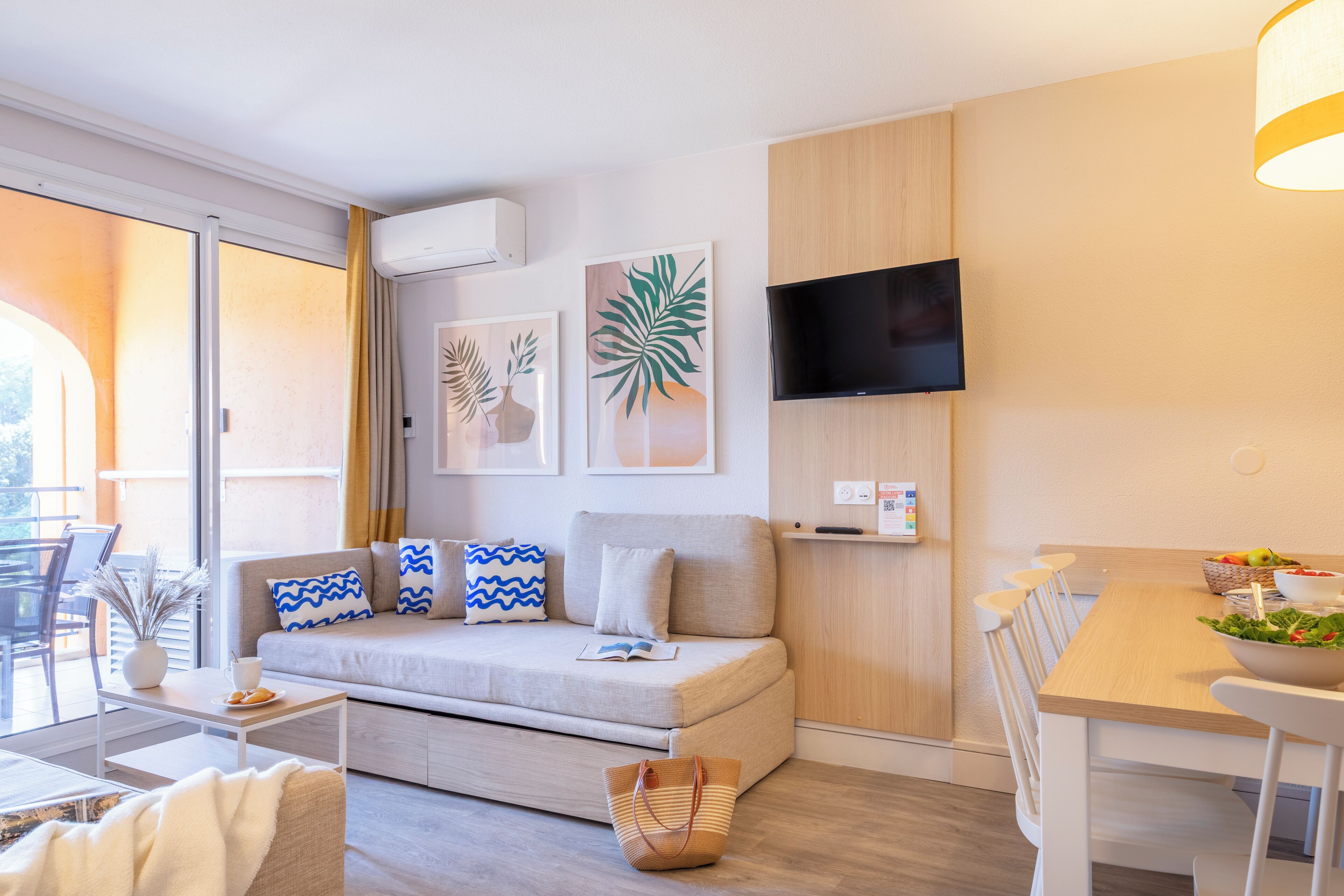 Ein modernes Wohnzimmer mit einer Couch, einem Esstisch und einem an der Wand befestigten Fernseher.