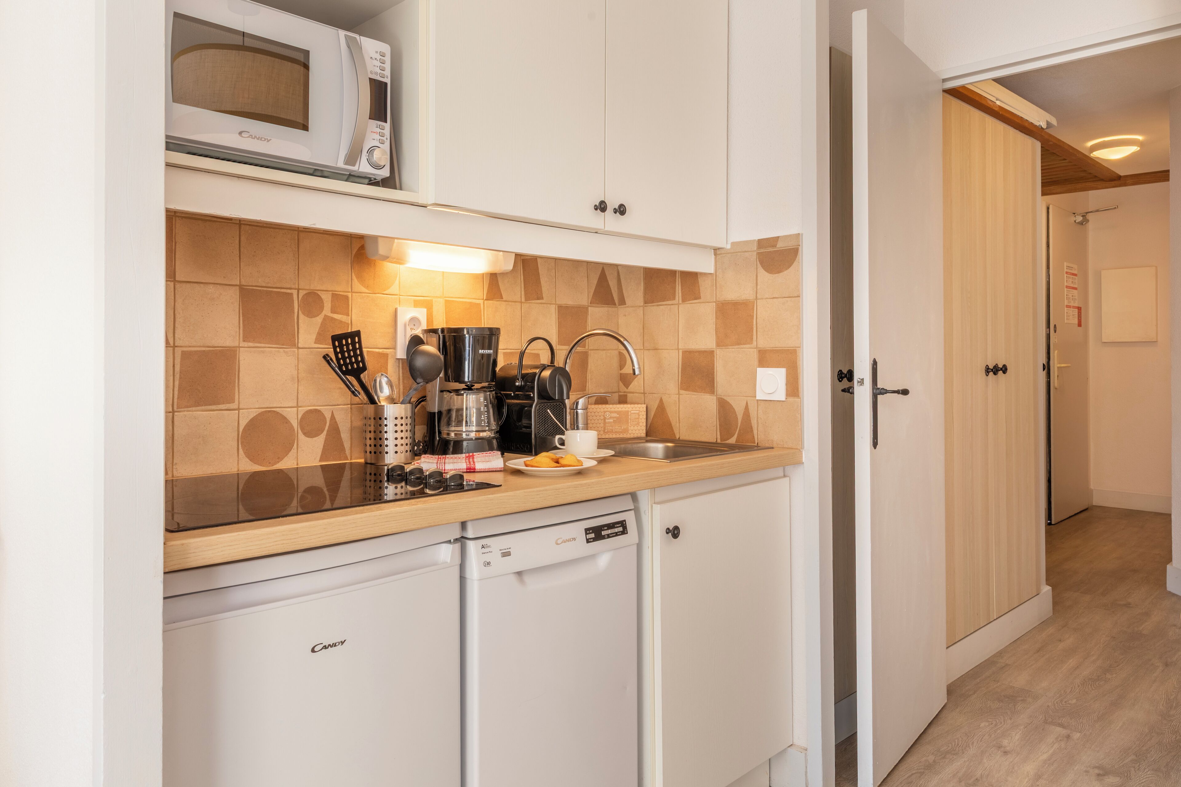 A compact kitchen with a microwave, coffee maker, and a small dishwasher.