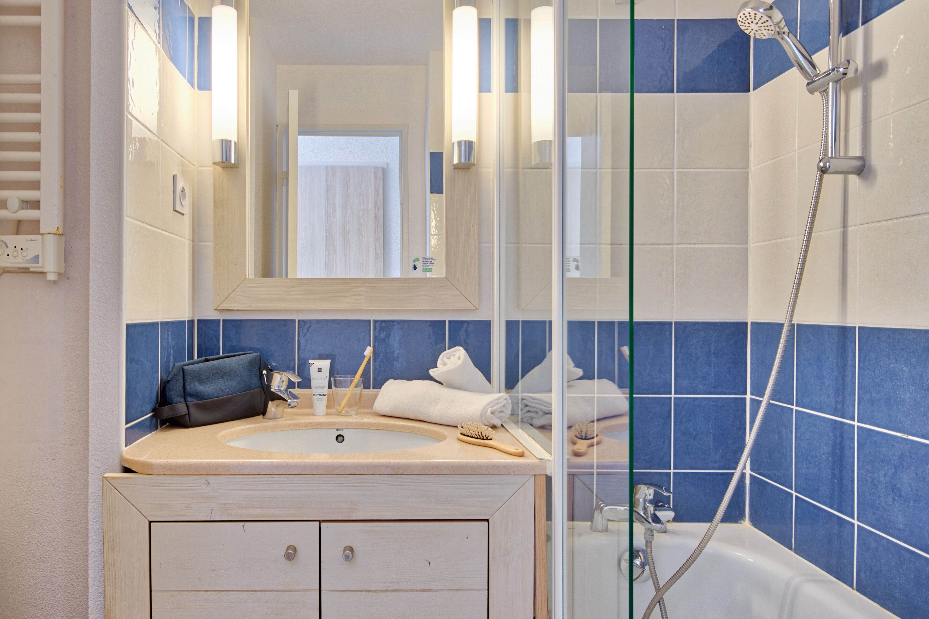 A bathroom with a sink, mirror, and shower.