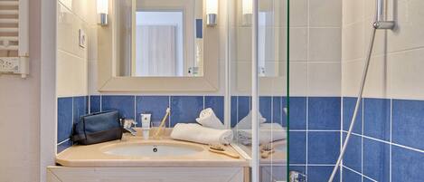 A bathroom with a sink, mirror, and shower.