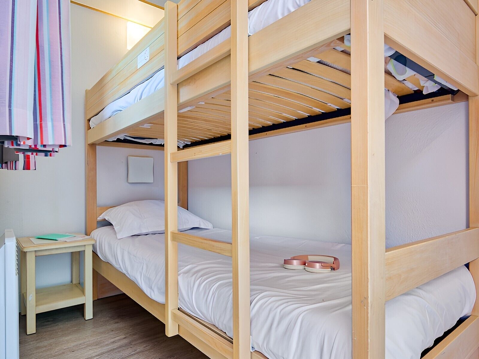 Habitación con literas, una mesita pequeña y un perchero.