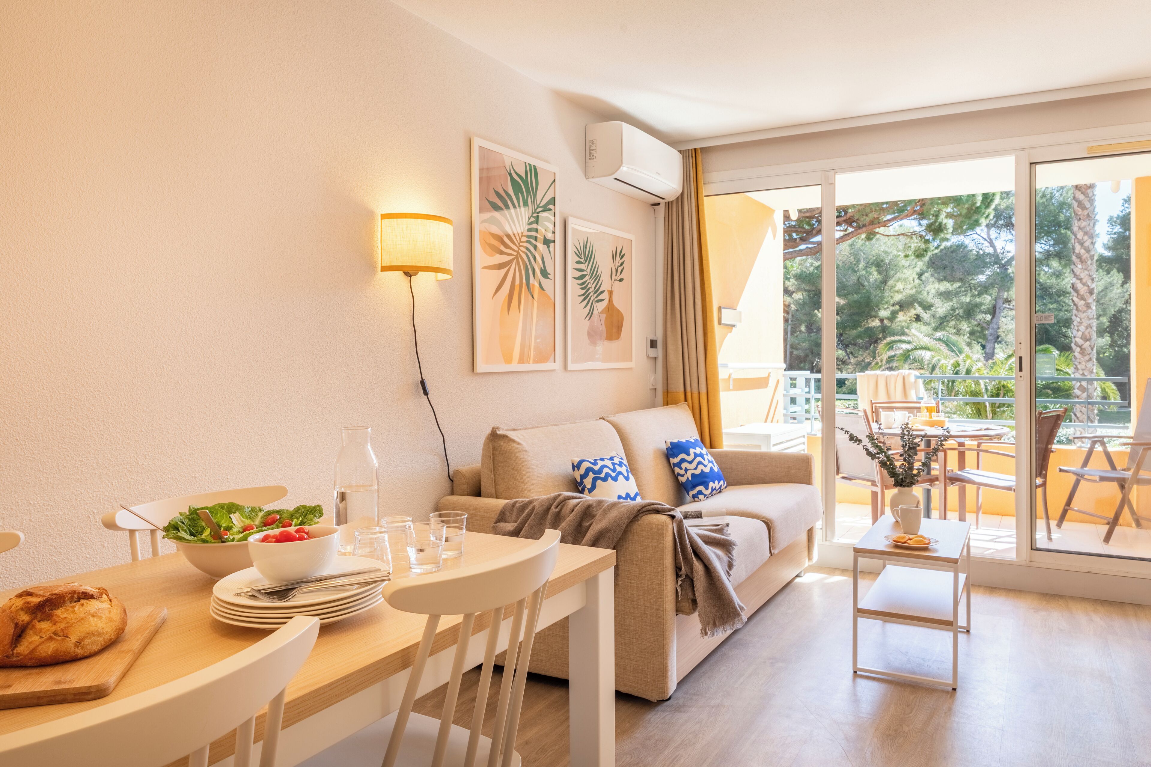 Ein modernes Wohnzimmer mit Essbereich, einer Couch, einem Couchtisch und einem Balkon mit Gartenmöbeln.