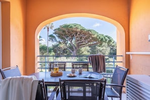 A balcony with a table set for two, overlooking a tree and a clear sky. - Pierre & Vacances Residence La Pinede (Hyères)