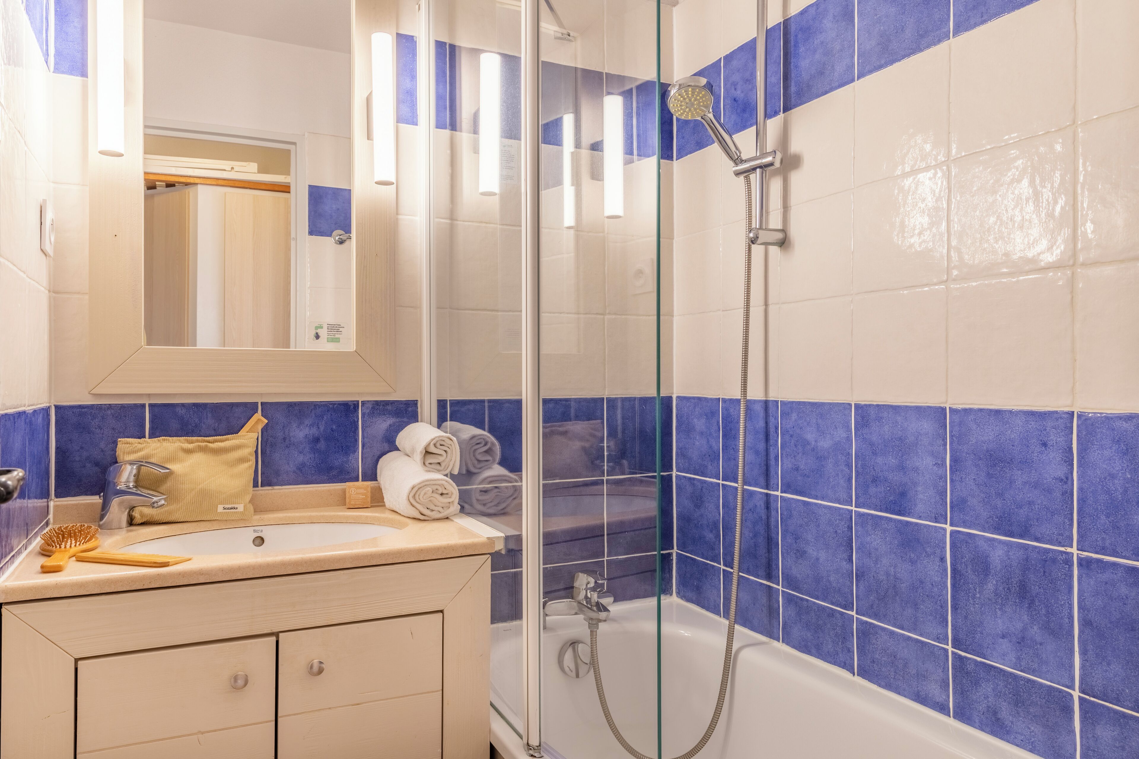 A bathroom with a sink, mirror, and shower.