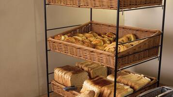 Ein mehrstufiges Brotregal mit verschiedenen Brotsorten und einem Toaster auf einer Holztischplatte.