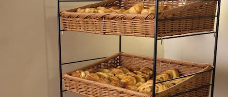 A multi-tiered bread rack with various types of bread and a toaster on a wooden surface.