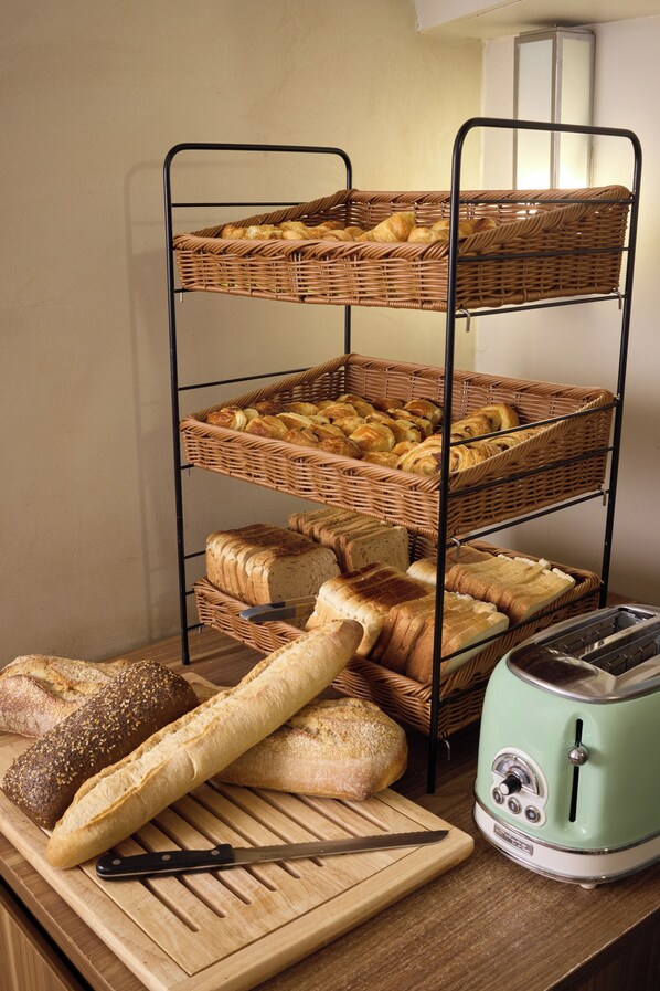 Un carrusel escalonado para pan con diferentes tipos de pan y un tostador sobre una superficie de madera.