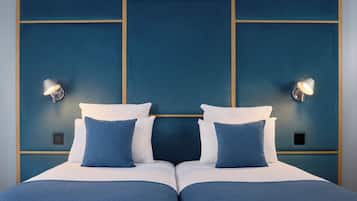 A double bed with two pillows, a bedside table, and a wall with two wall-mounted lamps.