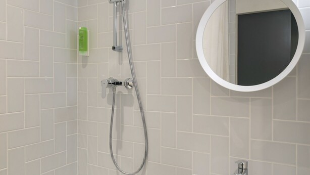 A modern bathroom with a shower, a sink, and a mirror. - Hôtel Sanso by HappyCulture (Ex Quality Bercy Bibliotèque) (Paris)