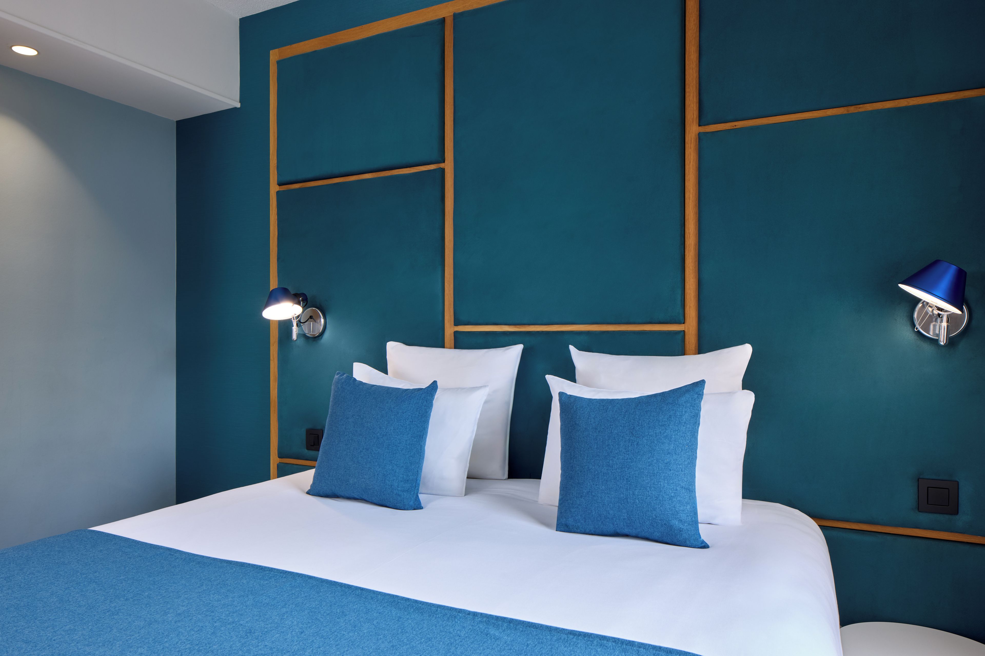 Een hotelkamer met een groot bed, twee nachtkastjes, een wandlamp en een nachtkastje.