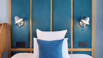 Une chambre d’hôtel avec un grand lit, deux lampes fixées au mur et une tête de lit en bois.