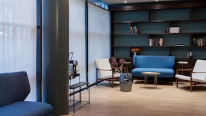 Un espace détente moderne avec un canapé bleu, une table basse ronde et une bibliothèque.