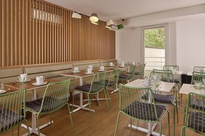 A modern cafe with wooden slatted walls, green metal chairs, and white tables. - Hôtel Sanso by HappyCulture (Ex Quality Bercy Bibliotèque) (Paris)