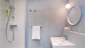 A modern bathroom with a shower, a sink, a mirror, and a towel rack. - Hôtel Sanso by HappyCulture (Ex Quality Bercy Bibliotèque) (Paris)