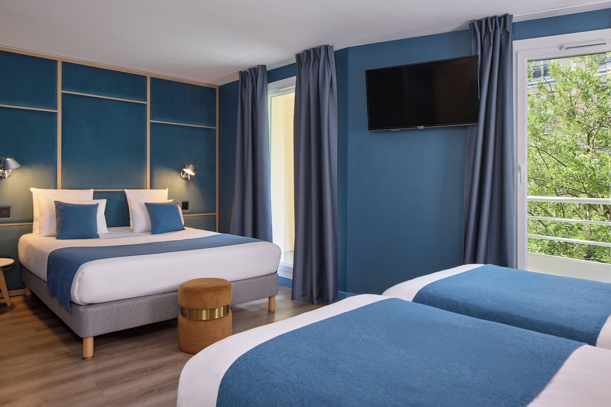 A hotel room with a bed, a TV, and a window with curtains.