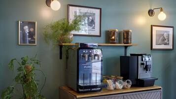 Eine Kaffeebar mit einer Purozza-Espressomaschine, zwei wandmontierten Kaffeeausgabegeräten und gerahmten Kunstwerken an der Wand.