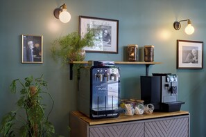 A coffee bar with a Purozza espresso machine, two wall-mounted coffee dispensers, and framed artwork on the wall. - Hôtel Sanso by HappyCulture (Ex Quality Bercy Bibliotèque) (Paris)