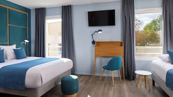Ein Hotelzimmer mit Bett, Schreibtisch, Stuhl, Fernseher und einem Fenster mit Vorhängen.