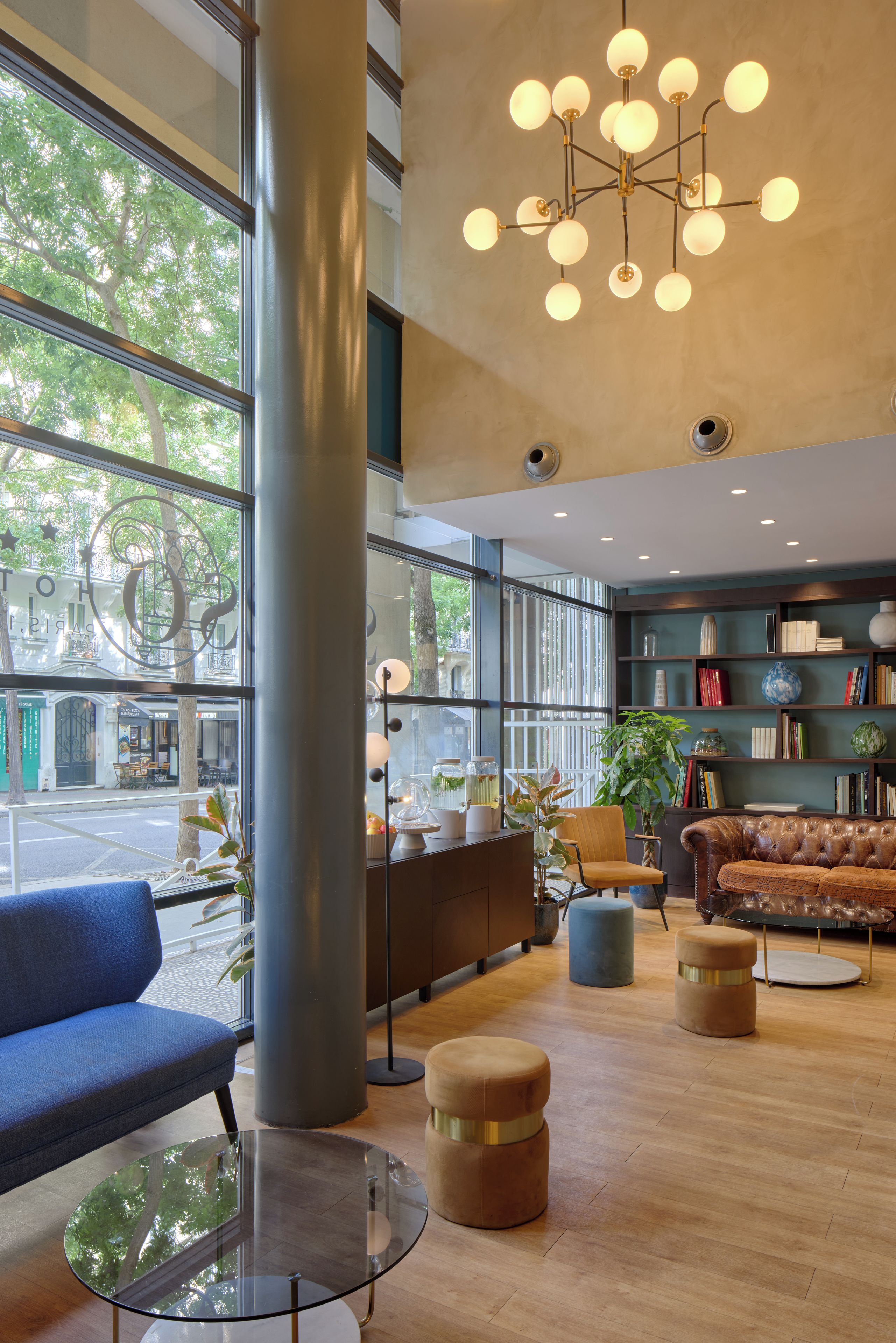 Een modern interieur met een groot raam, een ronde glazen tafel, een leren bank en een boekenplank.