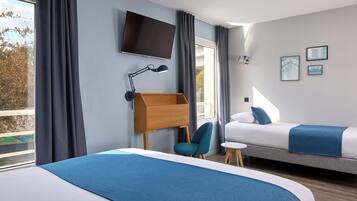 Ein Hotelzimmer mit Bett, Schreibtisch mit Stuhl, Wandfernseher und einem Fenster mit Vorhängen.