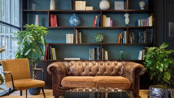 Una sala de estar acogedora con un sofá de cuero, una mesa de centro de vidrio y una estantería llena de libros.