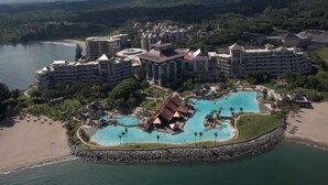 A resort with multiple buildings, a central pool area, and a beach.