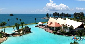 Un resort con una gran piscina, vistas a la playa y palmeras.