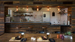 Un área de bar rústica con paredes de ladrillo visto, vigas de madera y lámparas colgantes.
