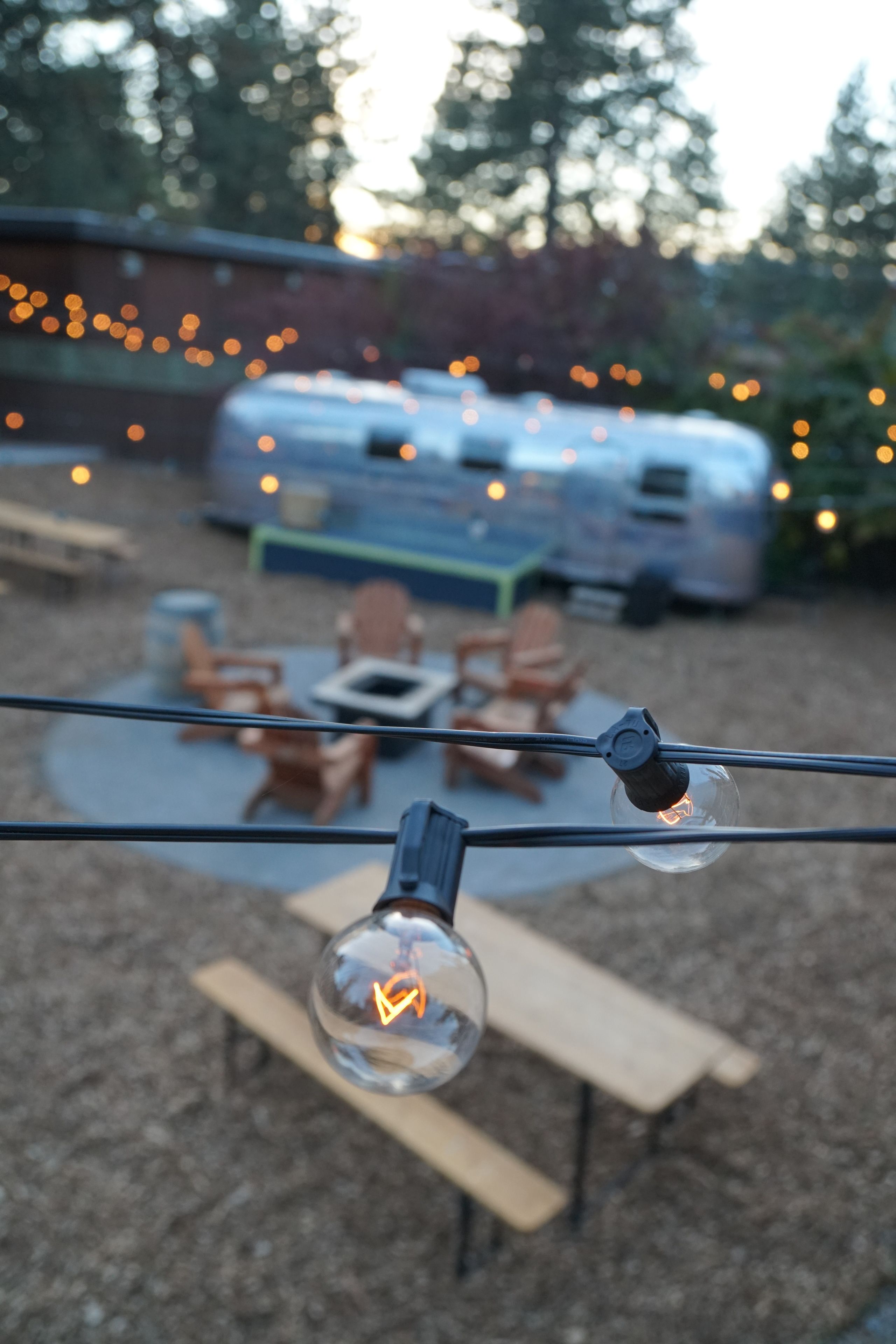 A backyard with a patio area, outdoor seating, and string lights.