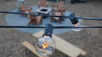 A backyard with a patio area, outdoor seating, and string lights.