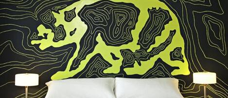 A bed with a headboard featuring a topographic map design, flanked by two bedside tables with lamps.
