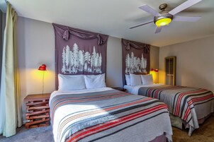 A hotel room with two beds, a ceiling fan, and a nightstand with a lamp.