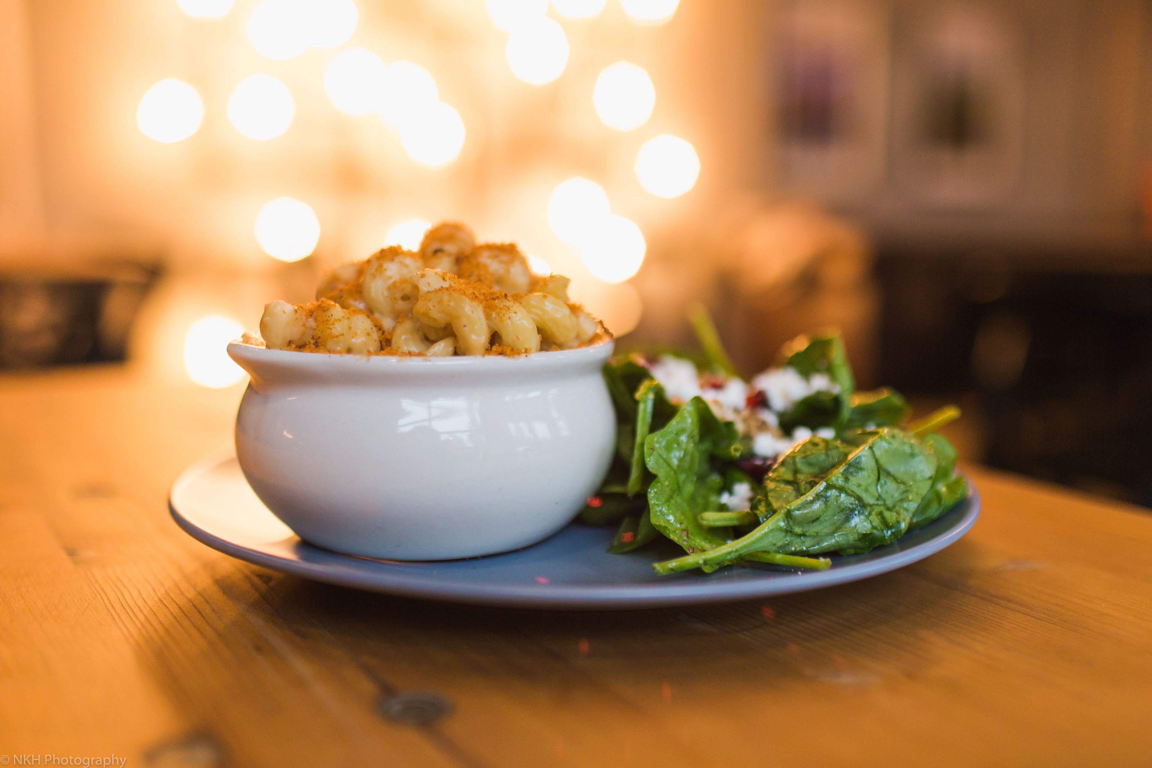 A bowl of macaroni and cheese with a side salad on a plate.