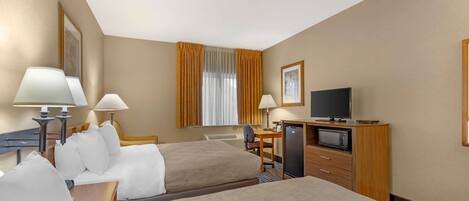 A hotel room with two beds, a desk with a computer, a TV, and a microwave.