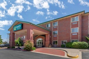 Un edificio de ladrillo con un toldo verde y un cartel que dice 'Quality Inn & Suites'.