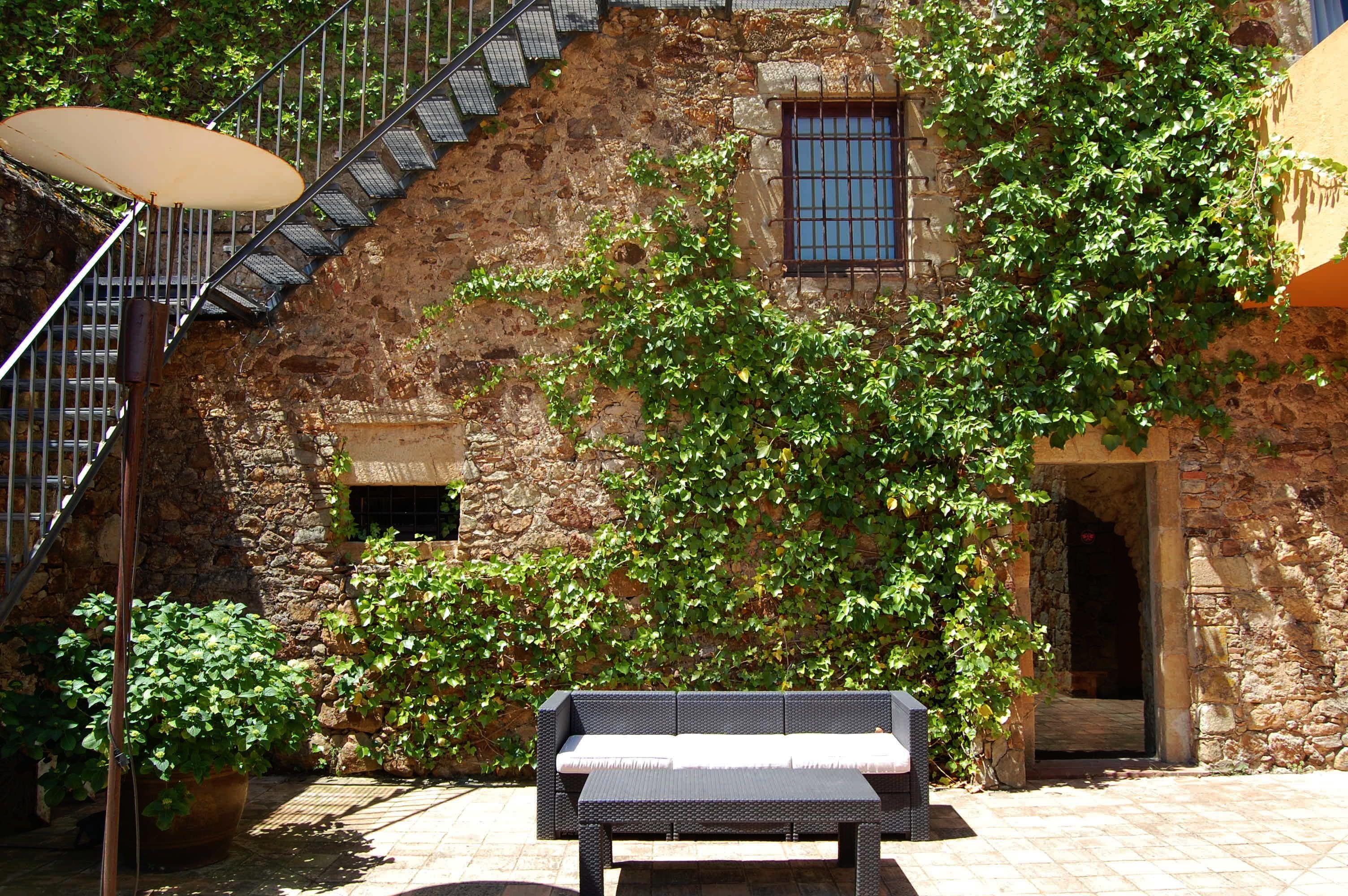 A stone building with a staircase, a bench, and a potted plant.