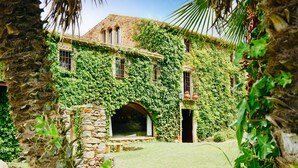 A stone building with ivy-covered walls and a central arched doorway. - Mas Salvi Country Boutique Hotel (Pals)