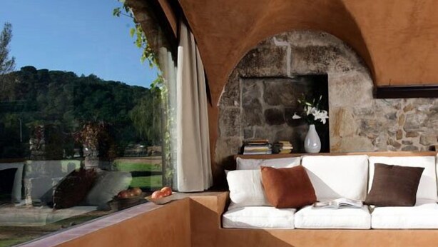A cozy room with a stone wall, a white sofa, and a view of a lush green landscape. - Mas Salvi Country Boutique Hotel (Pals)
