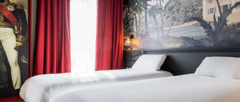 A hotel room with two beds, red curtains, a large portrait on the wall, and a mural depicting a tropical landscape.