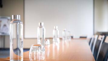Une salle de conférence avec une longue table en bois et plusieurs bouteilles en verre transparent.