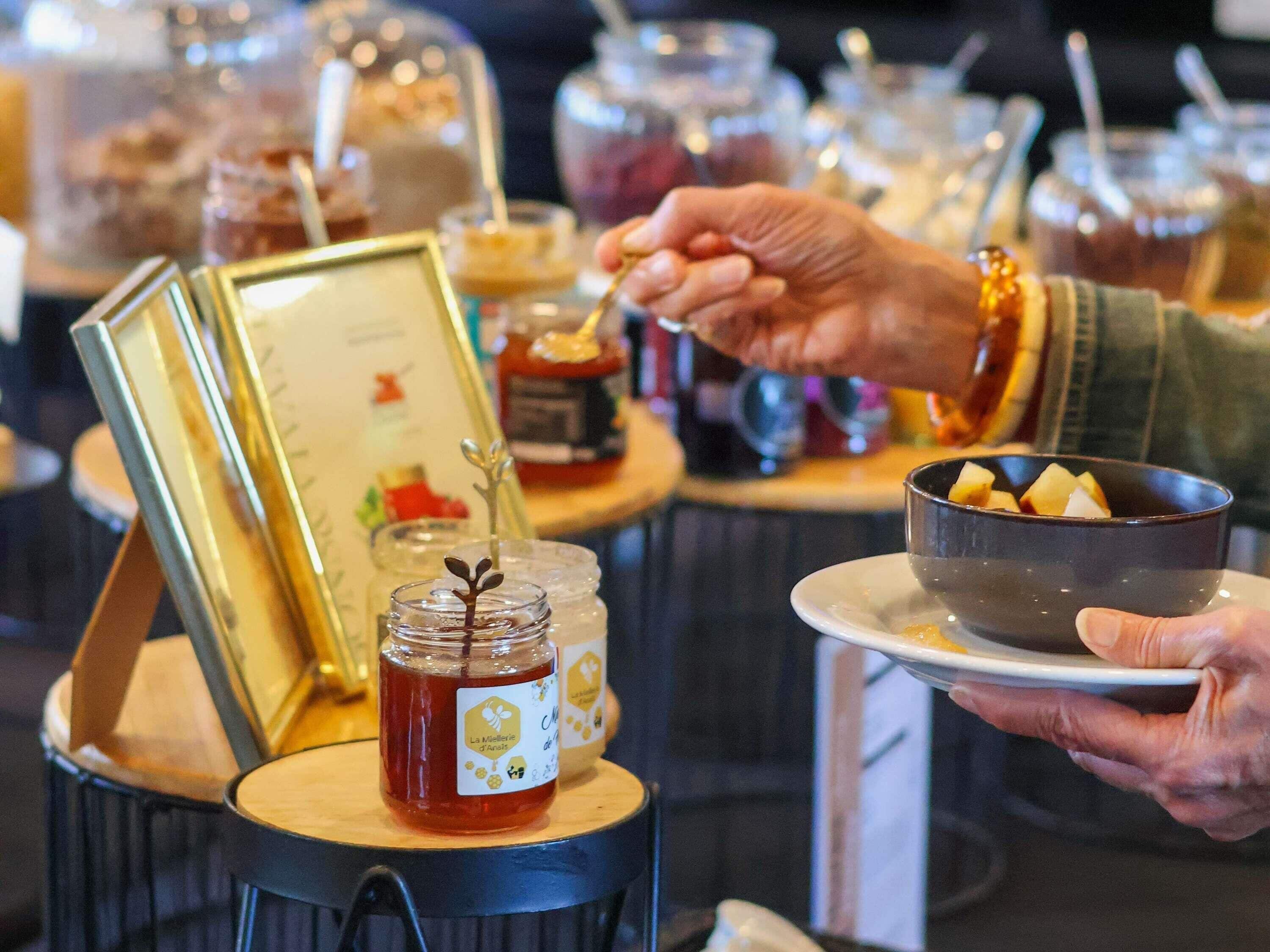 A person serving themselves food from a buffet with various dishes and condiments.