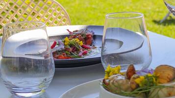 A dining table with two clear glasses, a plate with a salad, and a bowl of food.