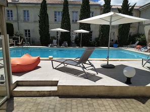 A pool area with lounge chairs, umbrellas, and a hot tub. - Mercure Rochefort La Corderie Royale (Rochefort)